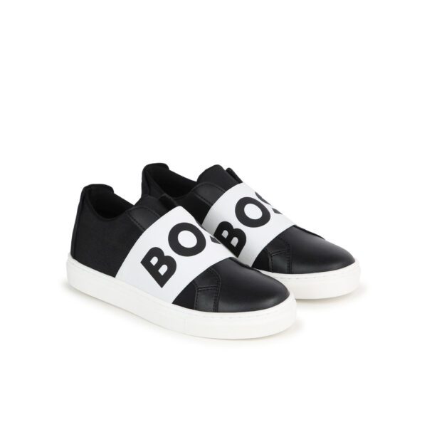 Stylish BOSS kids sneakers in black and white featuring a prominent logo print. These premium leather shoes are designed for comfort with a slip-on style and elasticated logo band. The high-quality calf leather upper and durable rubber sole provide both luxury and practicality, making them perfect for everyday wear. Ideal for young fashionistas looking for a modern touch in their footwear collection, available at Lestyle Boutique Melbourne.