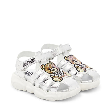 Moschino Kids metallic silver leather sandals featuring a Teddy Bear appliqu??, round toe, and Velcro ankle strap, available at Lestyle Boutique 136 Little Collins St.