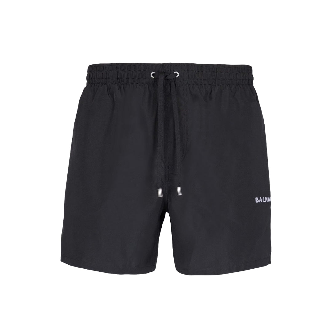 Premium Balmain black swim shorts featuring an elasticated drawstring waist for a comfortable fit. These luxury designer shorts showcase silver metal eyelets and aglets, along with two side pockets for practicality. The iconic Balmain logo is printed on the side, adding a touch of sophistication. Crafted from high-quality 100% polyester, these shorts are perfect for beach outings or poolside lounging, available at Lestyle Boutique Melbourne.
