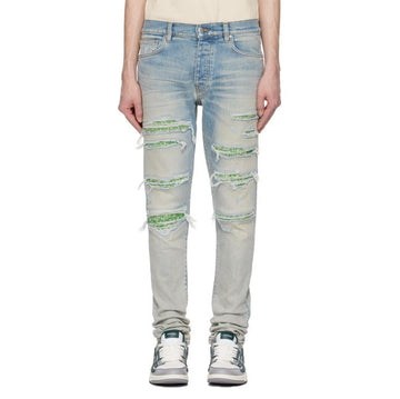 A pair of antiqued indigo stretch skinny jeans by AMIRI, available at Lestyle Boutique. These jeans feature a stonewashed and distressed finish with repaired rips, belt loops, and a contrasting logo label for a contemporary look.