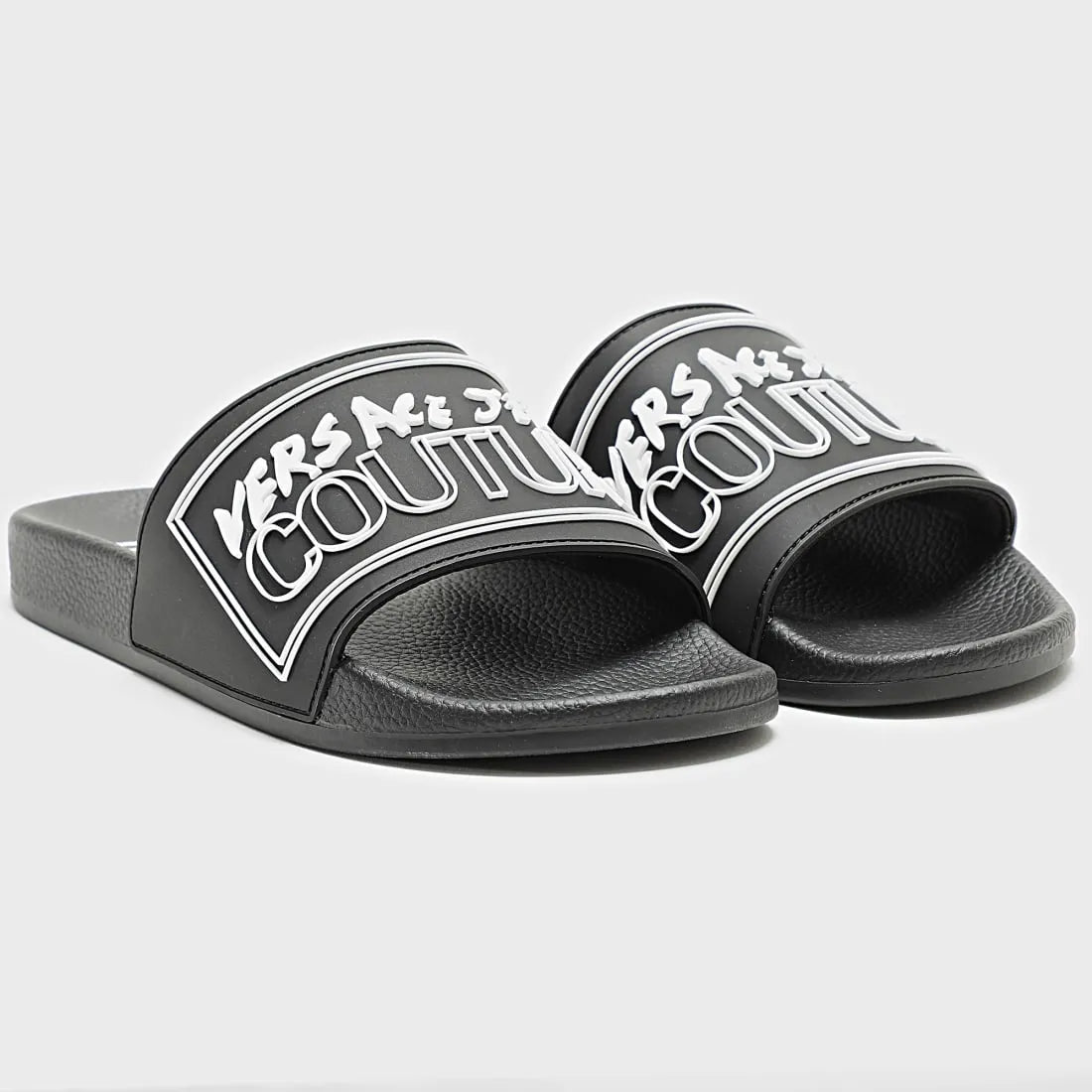 Versace Jeans Couture slides in black with an embossed white logo, featuring a slip-on design and cushioned sole for comfort and effortless style, available at Lestyle Boutique.