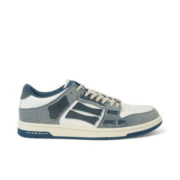 A pair of slate blue vintage denim low-top sneakers by AMIRI, available at Lestyle Boutique. Featuring a unique patchwork design, logo details, and a flat rubber sole for comfort and style.