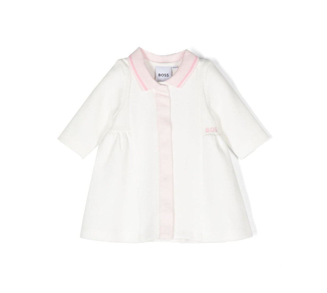 BOSS kidswear dress in off-white with light pink accents, featuring a premium cotton blend for comfort. This stylish dress includes a classic polo collar and long sleeves, perfect for young girls. The embroidered logo adds a designer touch, making it ideal for special occasions or everyday wear. Designed with a concealed front button fastening and a straight hem for a polished look, this dress is a must-have for fashionable kids. Available at Lestyle Boutique Melbourne.
