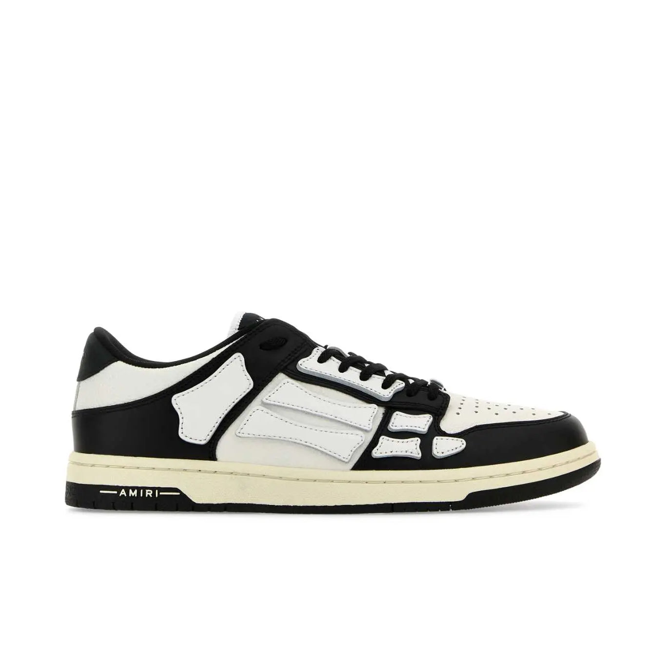 A pair of low-top white and black sneakers by AMIRI, available at Lestyle Boutique. These sneakers feature skeleton-inspired stitching, designer logo details, and a flat sole for comfort and a unique style.