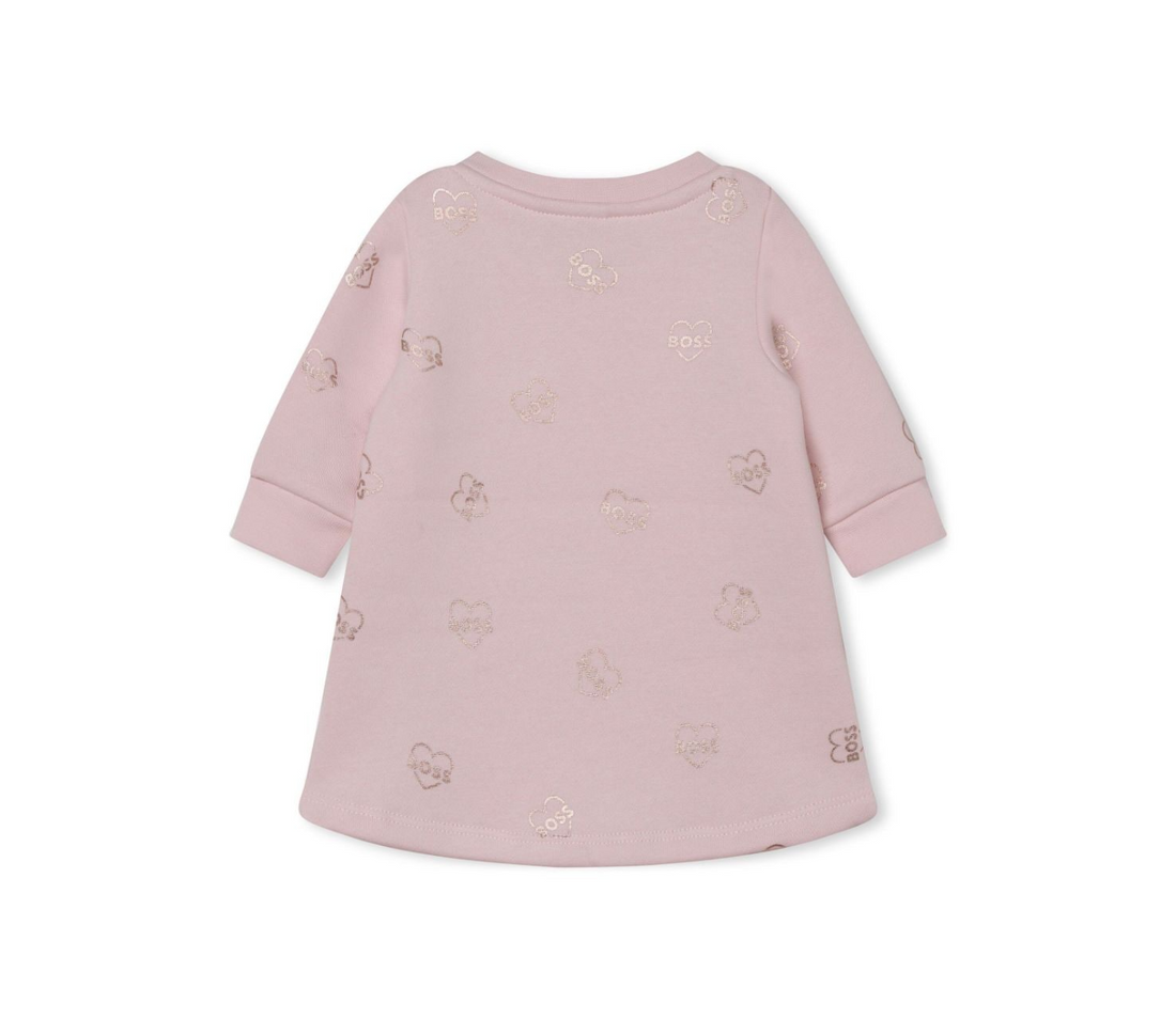 BOSS KIDSWEAR pale pink cotton dress featuring an all-over logo print with a metallic finish. This stylish crew neck design includes long sleeves, ribbed cuffs, and a curved hem, making it perfect for casual outings or special occasions. The heart motif adds a playful touch, while the button fastening at the shoulder ensures easy dressing. Crafted from high-quality organic cotton blend, this dress is both comfortable and fashionable for young girls, available at Lestyle Boutique Melbourne.