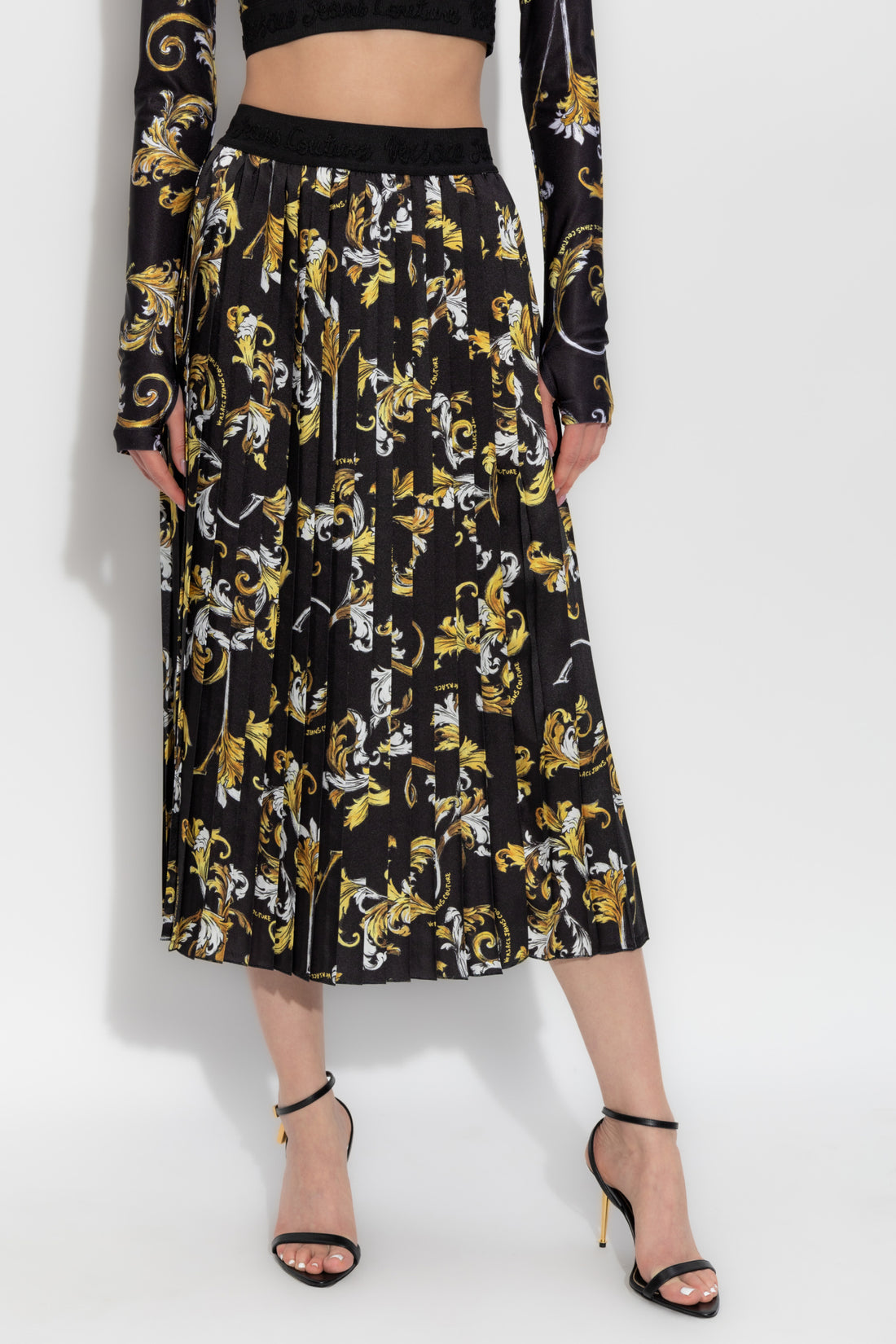 Versace Jeans Couture Black Pleated Skirt adorned with a stunning Outline Barocco print, showcasing timeless elegance and modern style, available at Lestyle Boutique.