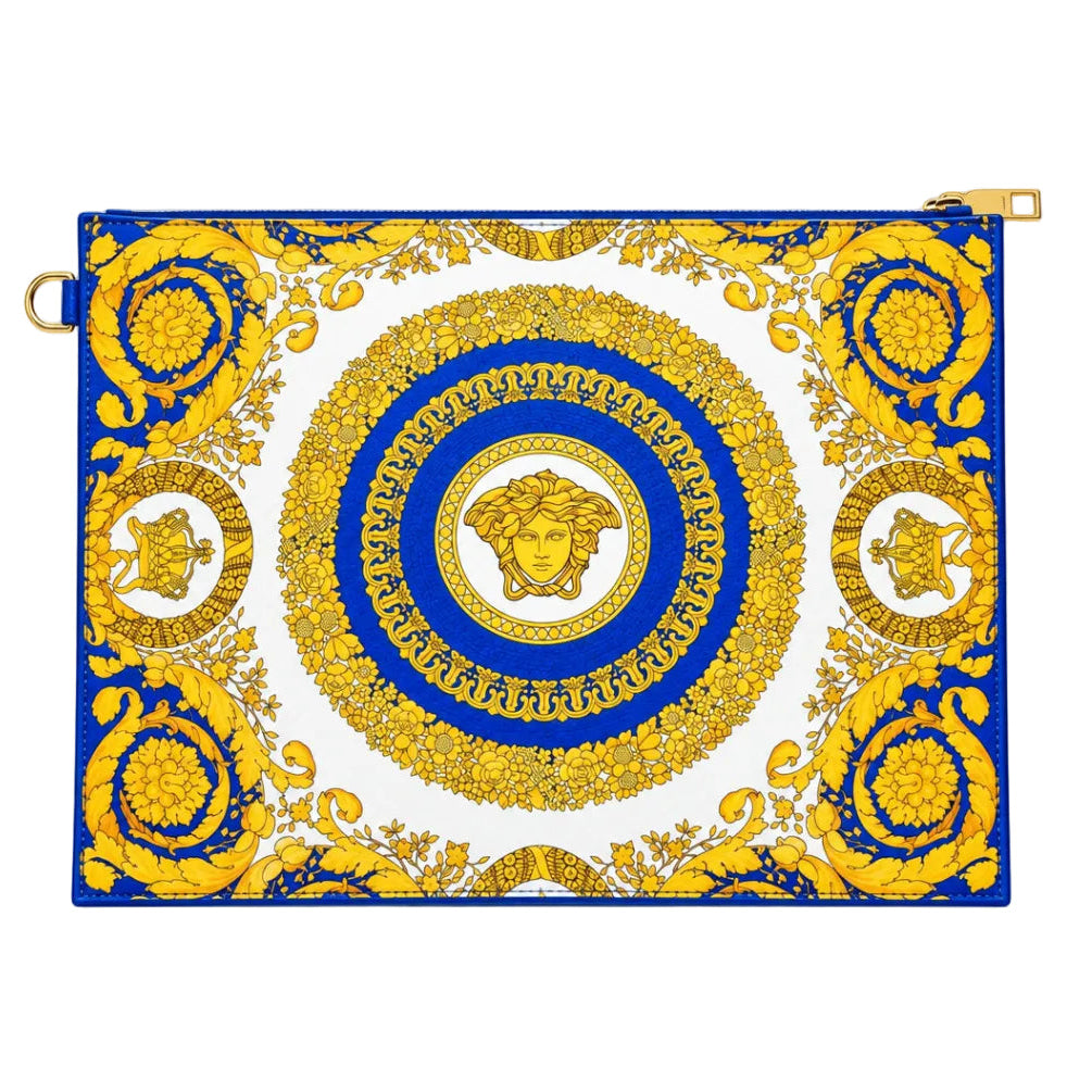 A rectangular handbag or clutch featuring a bold blue and gold baroque-style medallion pattern on a white background, displayed on a glass jewelry counter.