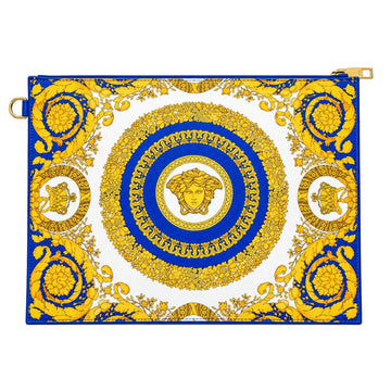 A rectangular handbag or clutch featuring a bold blue and gold baroque-style medallion pattern on a white background, displayed on a glass jewelry counter.