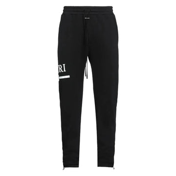 Black sweatpants with a white printed graphic on the left leg, featuring an elastic waistband with a drawstring and zippered cuffs.