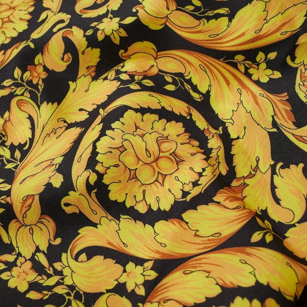 Versace swim trunks in black and gold with all-over baroque print, elasticated waistband, and adjustable drawcord, made in Italy, available at Lestyle Boutique 136 Little Collins St.
