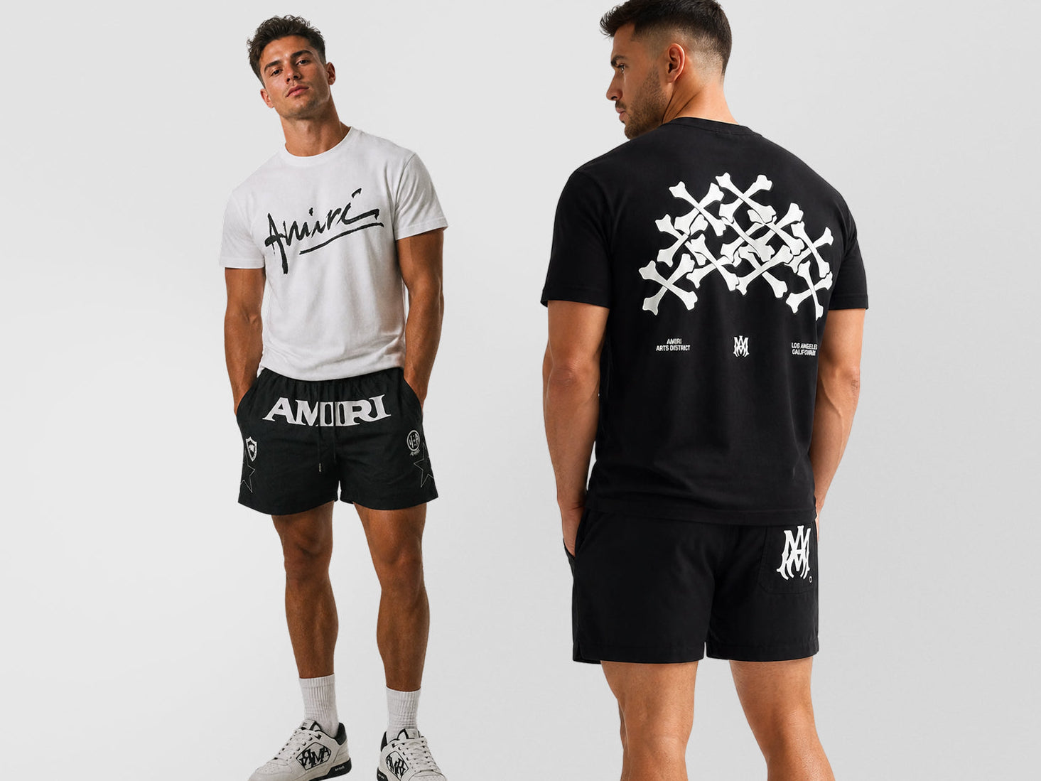 Two male models shown against a light gray studio background, displaying a matching athletic outfit. The model on the left wears a white t-shirt with a black script logo and black shorts with 'AMORI' printed in white.