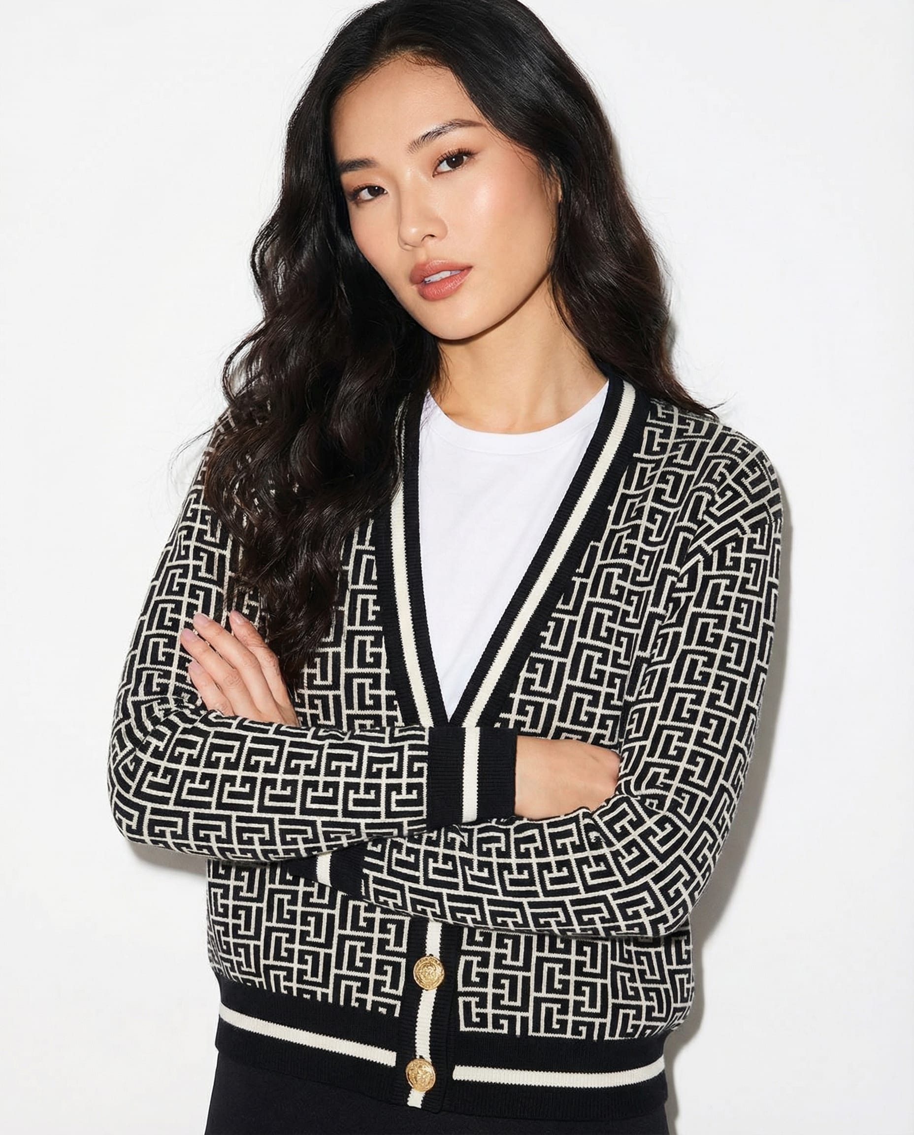Woman wearing a Balmain black and white patterned cardigan on a white background