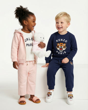 Two children in branded clothing with a white background