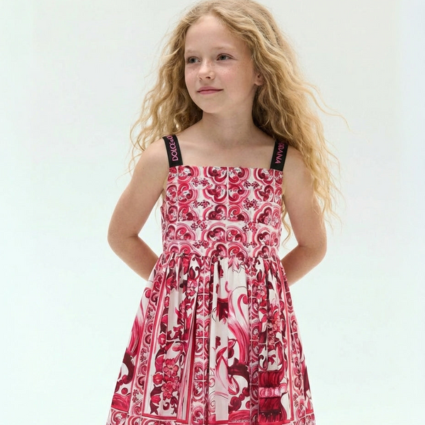 Young girl wearing a red and white patterned dolce & gabbana dress on a light gray background