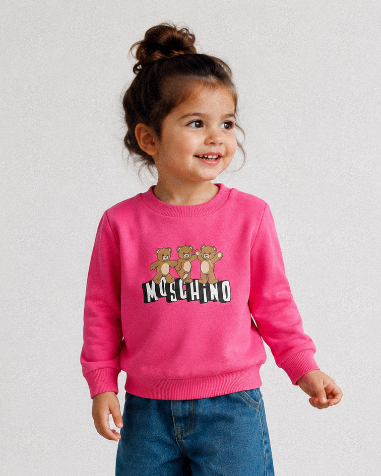 Child wearing a pink Moschino sweatshirt with teddy bear design on a light gray background