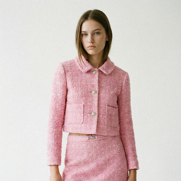 Woman wearing a pink tweed suit on a white background