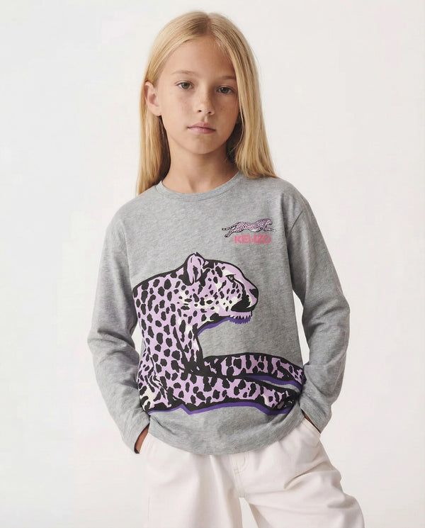 Young girl wearing a gray sweatshirt with a purple leopard design on a white background
