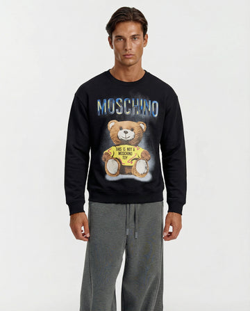 Man wearing a black Moschino sweatshirt with a bear graphic on a white background