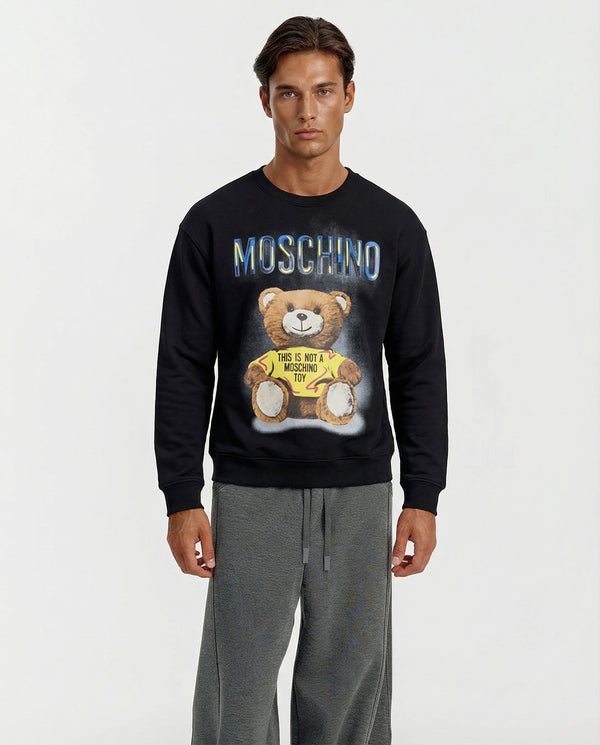 Man wearing a black Moschino sweatshirt with a bear graphic on a white background