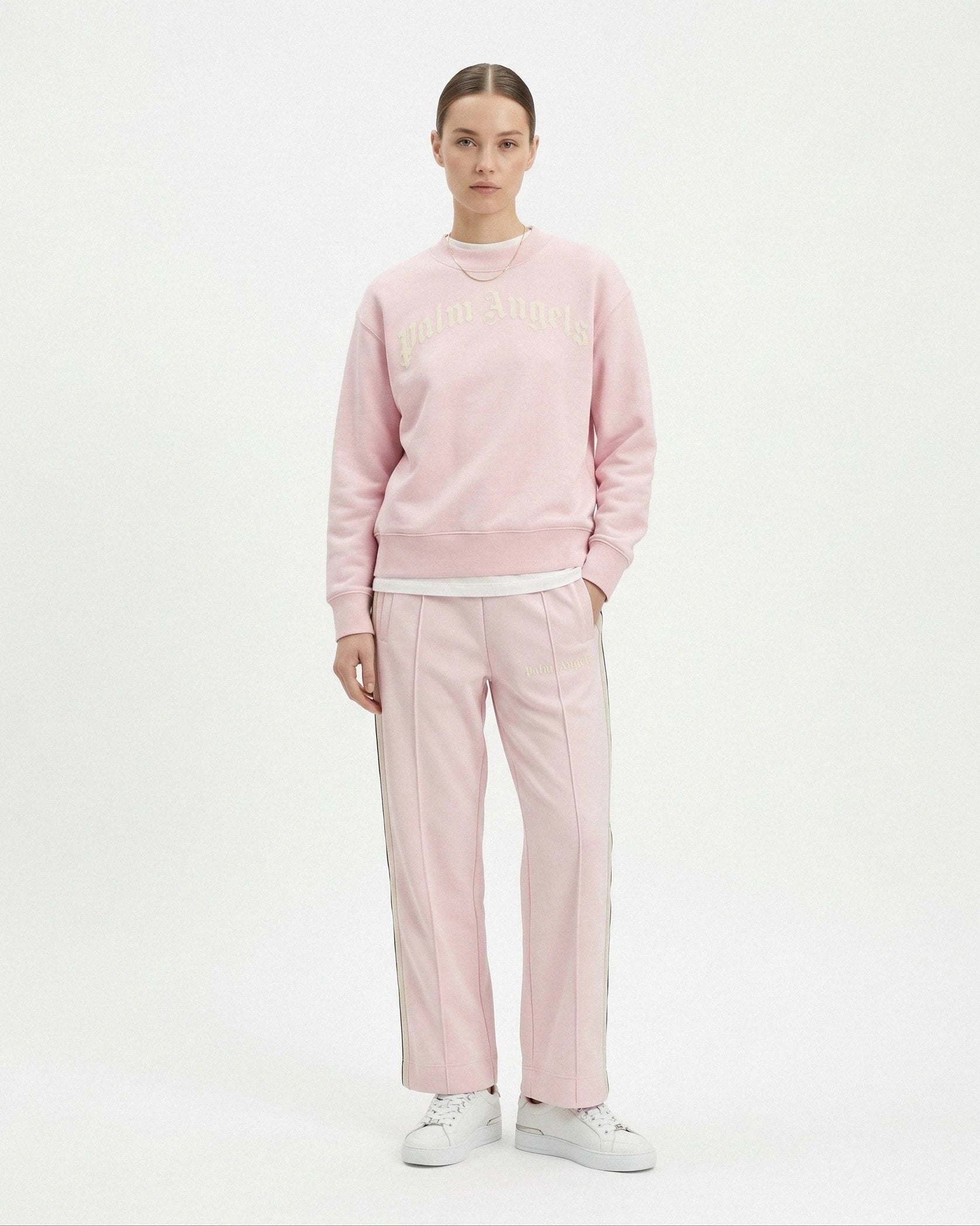 Person wearing a pink Palm Angels sweatshirt and pants on a white background