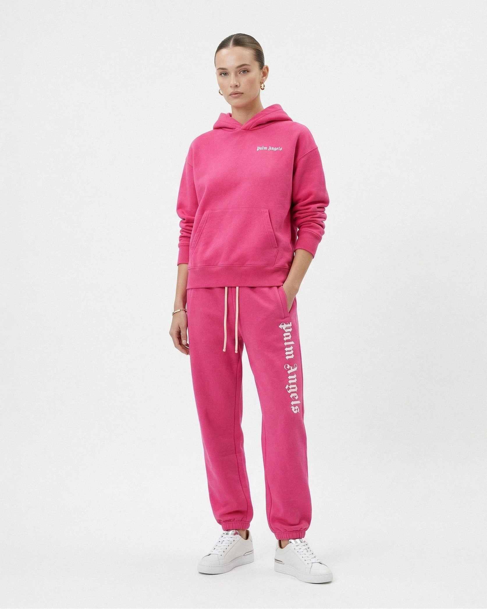Person wearing a pink tracksuit with 'Palm Angels' branding on a white background