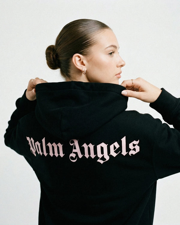 Person wearing a black hoodie with 'Palm Angels' logo on the back against a white background