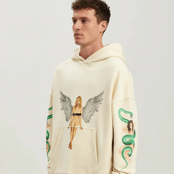 Man wearing a cream palm angels hoodie with artistic designs on a plain background
