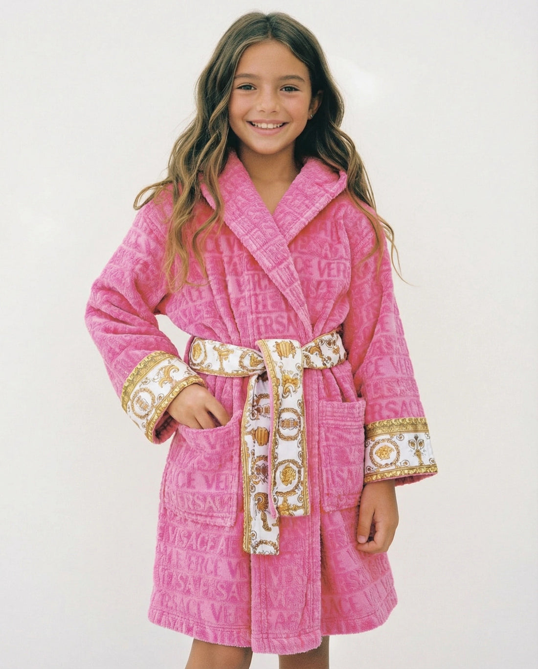 Versace Kids Belted Logo Monogram Hooded Robe in pink with gold baroque detailing, featuring an all-over Versace monogram print, a hooded design, and a belted waist, available at Lestyle Boutique.