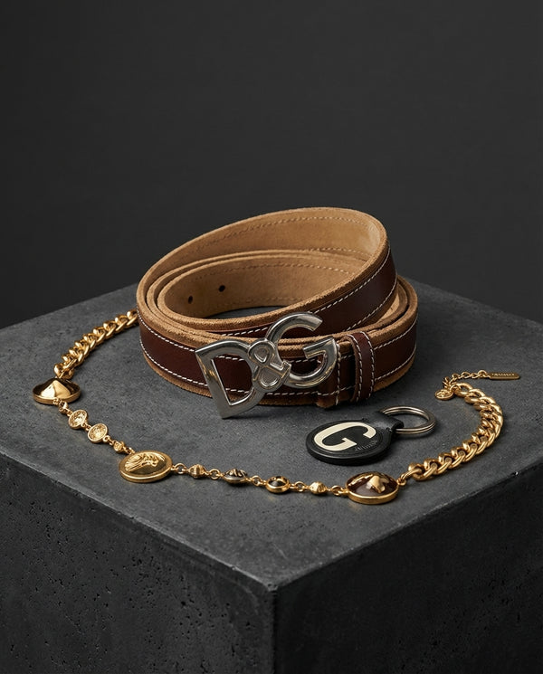 Brown leather belt with silver buckle and gold chain on a dark surface