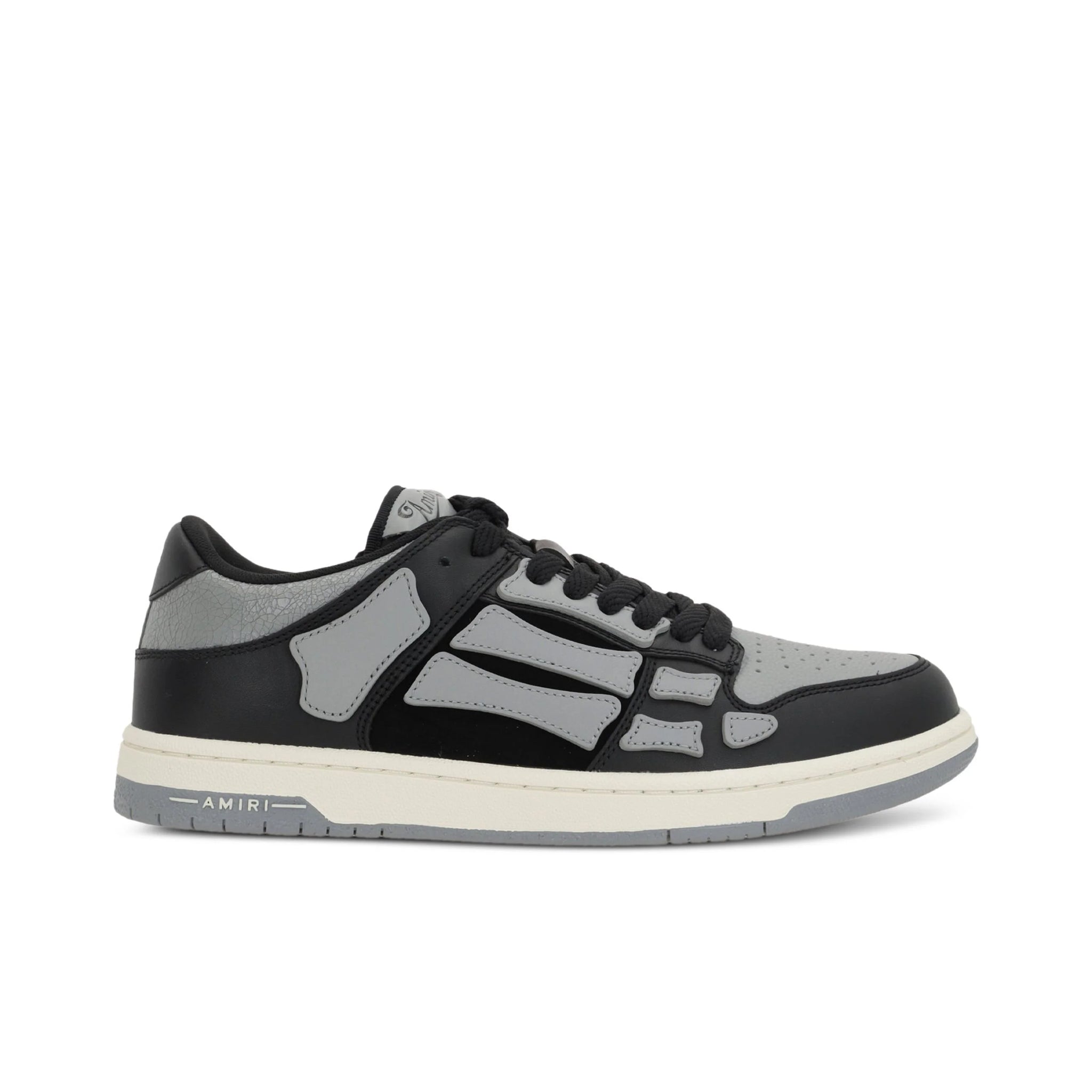 A pair of asphalt grey Skel Top low sneakers by AMIRI, available at Lestyle Boutique. Featuring sewn applications, two-tone rubber sole, and perforated details, these sneakers combine style and comfort effortlessly.