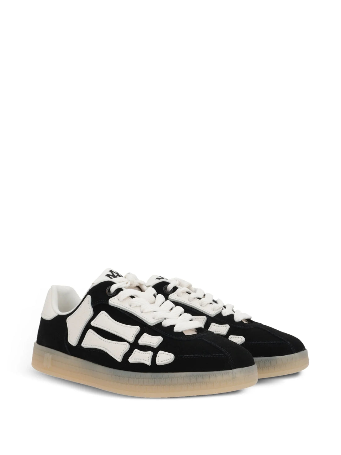 A pair of black Pacific Bones low-top sneakers by AMIRI, available at Lestyle Boutique. These sneakers feature a suede upper with skeleton motif overlays, leather applications, and a durable rubber sole with MA icon detailing.