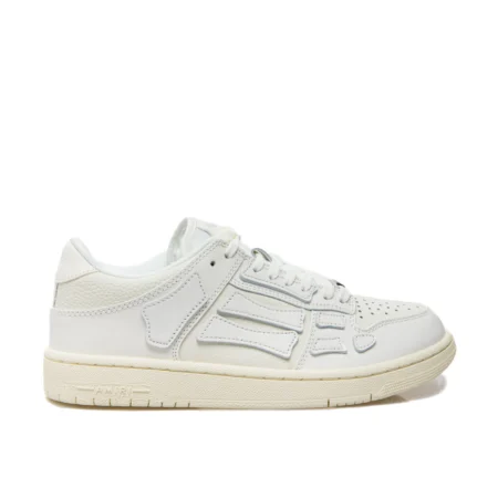 A pair of white low-top calfskin sneakers by AMIRI, available at Lestyle Boutique. These premium sneakers feature a perforated round toe, padded ankle, logo detailing, and a durable flat rubber sole for comfort and style.
